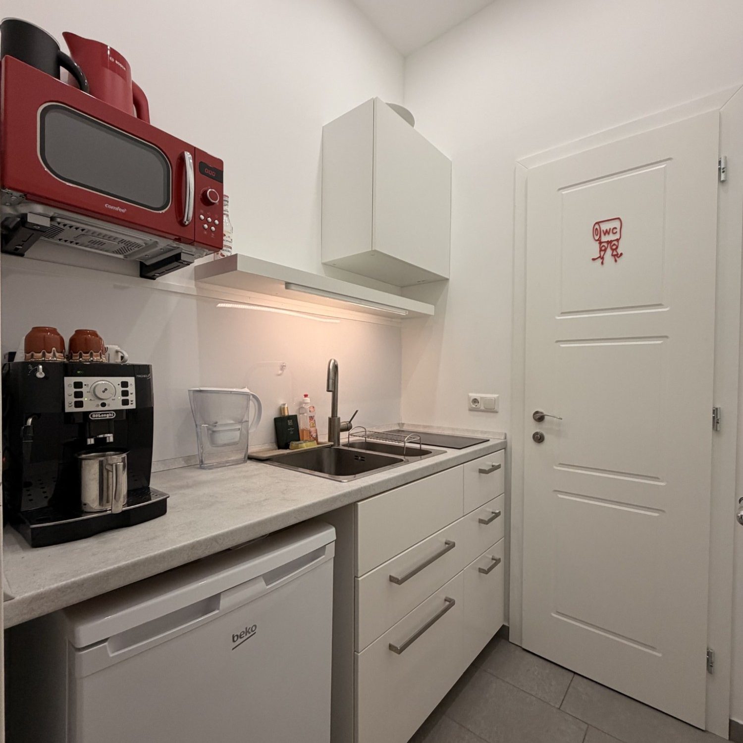 Die Küche mit Kaffeemaschine, Mikrowelle und Kühlschrank